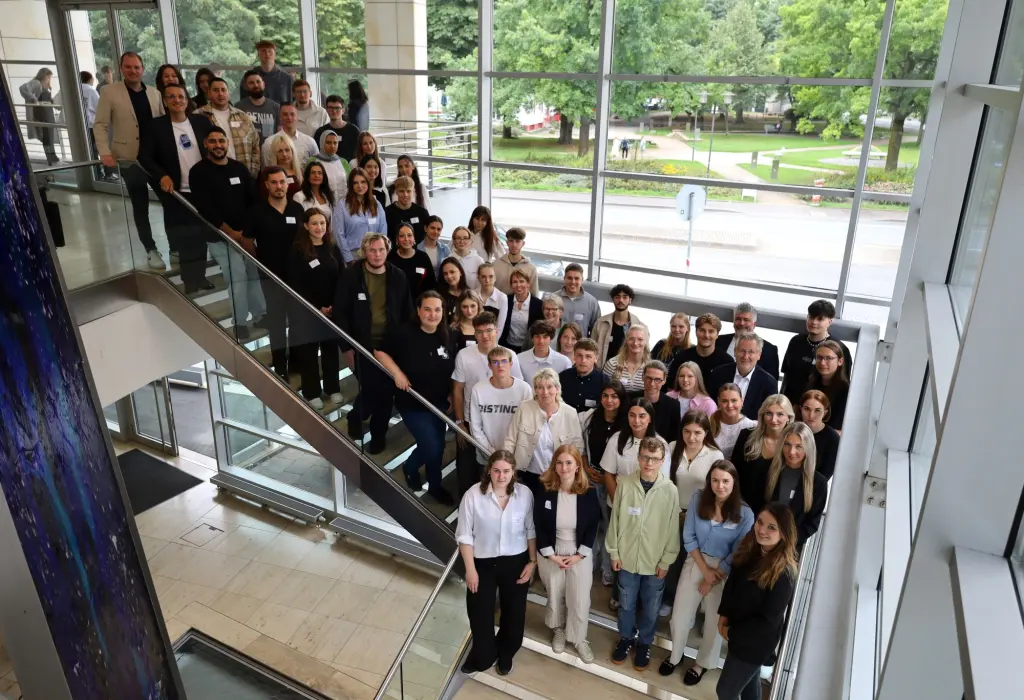 Foto: Von oben wird eine sehr große Gruppe an Menschen fotografiert, die auf einer Treppe stehen.