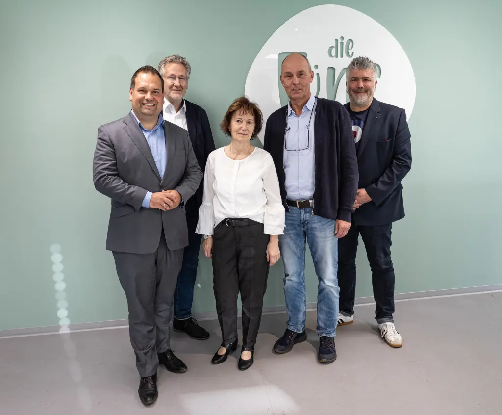 Foto: Fünf Personen stehen nebeneinander und lächeln in die Kamera.