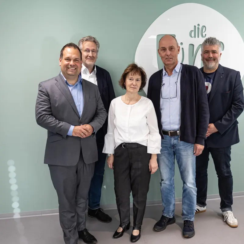 Foto: Fünf Personen stehen nebeneinander und lächeln in die Kamera.