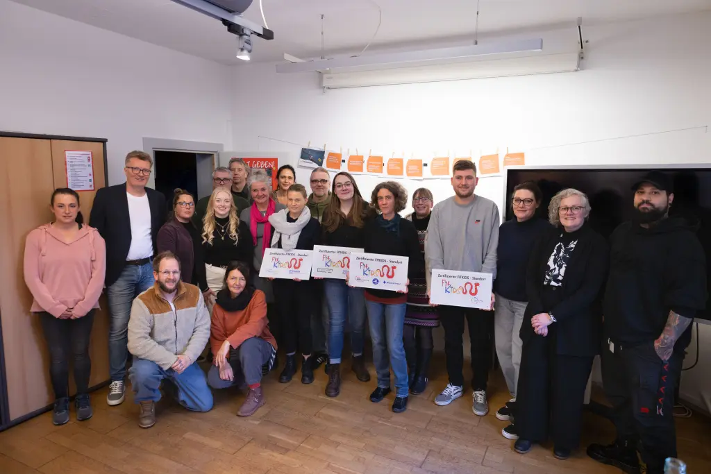 Foto: Mehrere Menschen stehen nebeneinander, vier von Ihnen halten Exemplare des Fitkids-Siegels in den Händen.