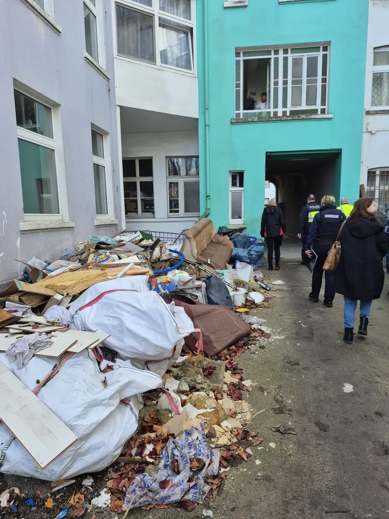 Foto: Zu sehen sind mehrere Müllhaufen in einem Innenhof sowie einige Ordnungskräfte.