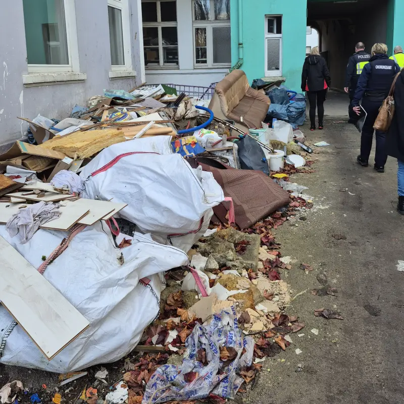 Foto: Zu sehen sind mehrere Müllhaufen in einem Innenhof sowie einige Ordnungskräfte.