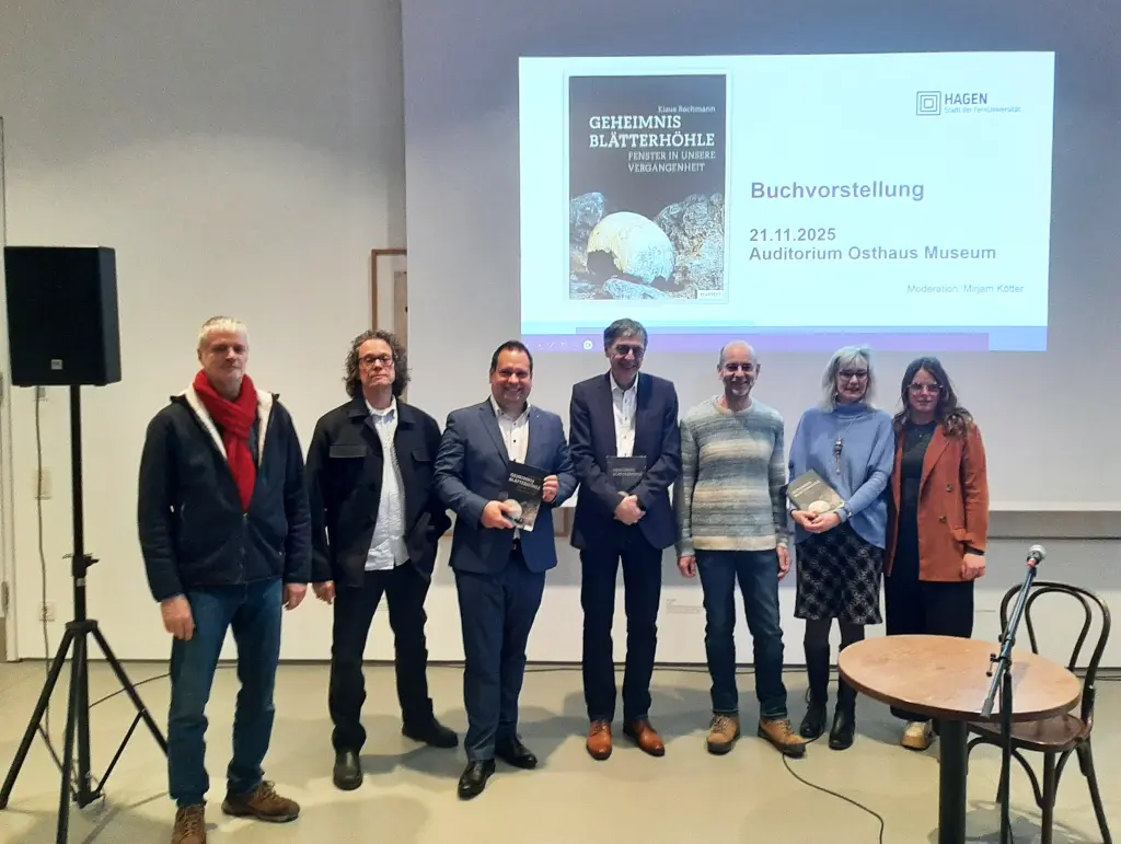 Foto: Sieben Personen stehen nebeneinander, drei von ihnen halten Bücher in den Händen.