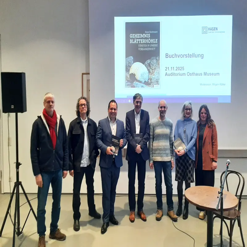 Foto: Sieben Personen stehen nebeneinander, drei von ihnen halten Bücher in den Händen.