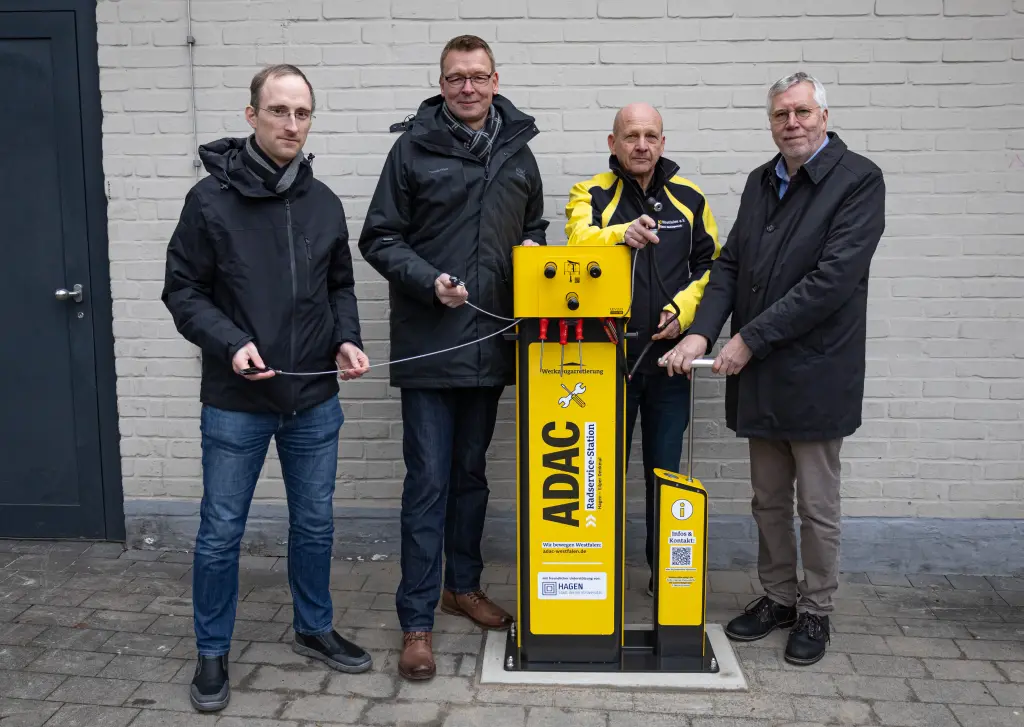 Foto: Die vier Beteiligten stehen neben der Radservice-Station am Eilper Denkmal und lächeln in die Kamera.