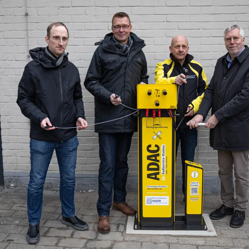 Foto: Die vier Beteiligten stehen neben der Radservice-Station am Eilper Denkmal und lächeln in die Kamera.