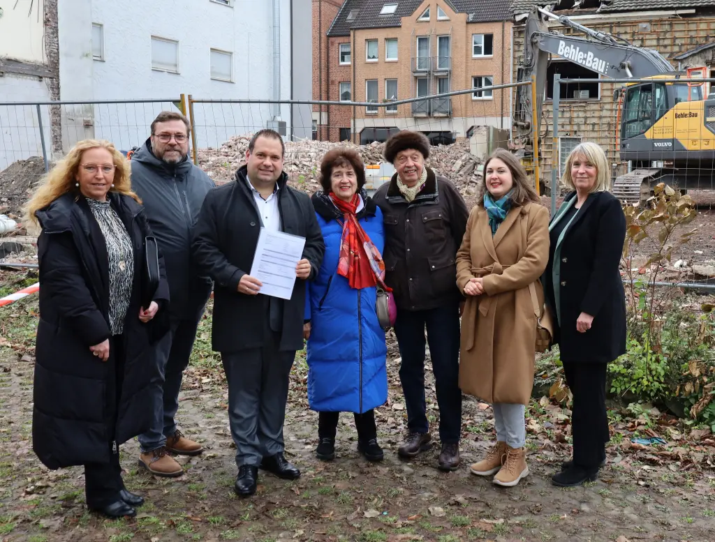Foto: Die Beteiligten stehen nebeneinander, Dennis Rehbein hält die Förderzusage in den Händen.