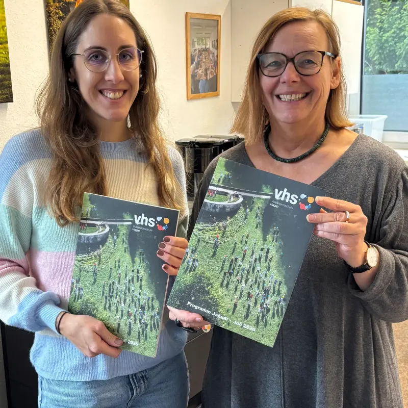 (v.l.) Sara Becker und Birgit Andrich aus dem Team der VHS halten jeweils ein neues Programmheft in den Händen.