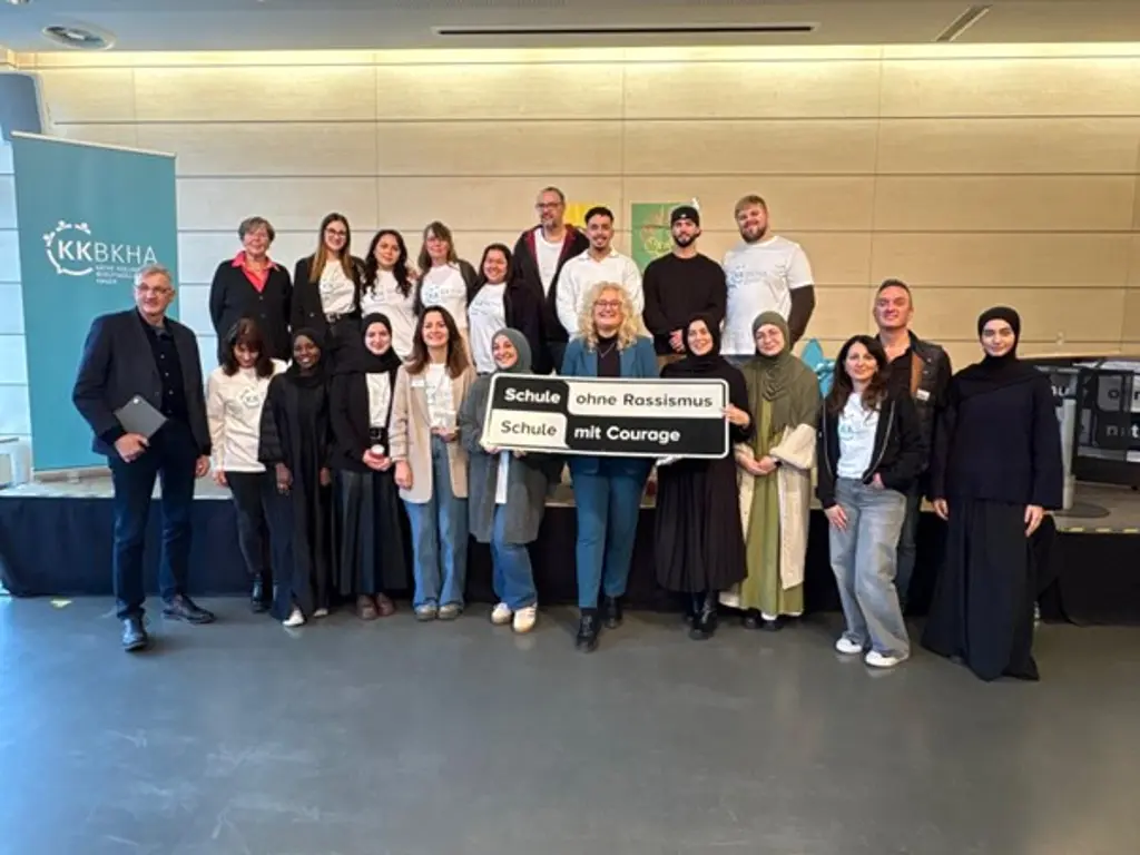 Foto: Gruppenfoto vieler Sch&uuml;lerinnen und Sch&uuml;ler, die ein Schild mit der Aufschrift &bdquo;Schule ohne Rassismus &ndash; Schule mit Courage&ldquo; pr&auml;sentieren.
