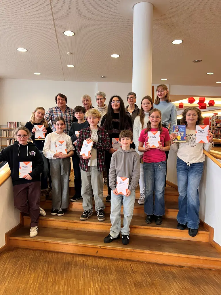 Gruppenfoto: Die Sch&uuml;lerinnen und Sch&uuml;ler sowie die Jury freuen sich &uuml;ber die tollen Leseleistungen beim Vorlesewettbewerb.