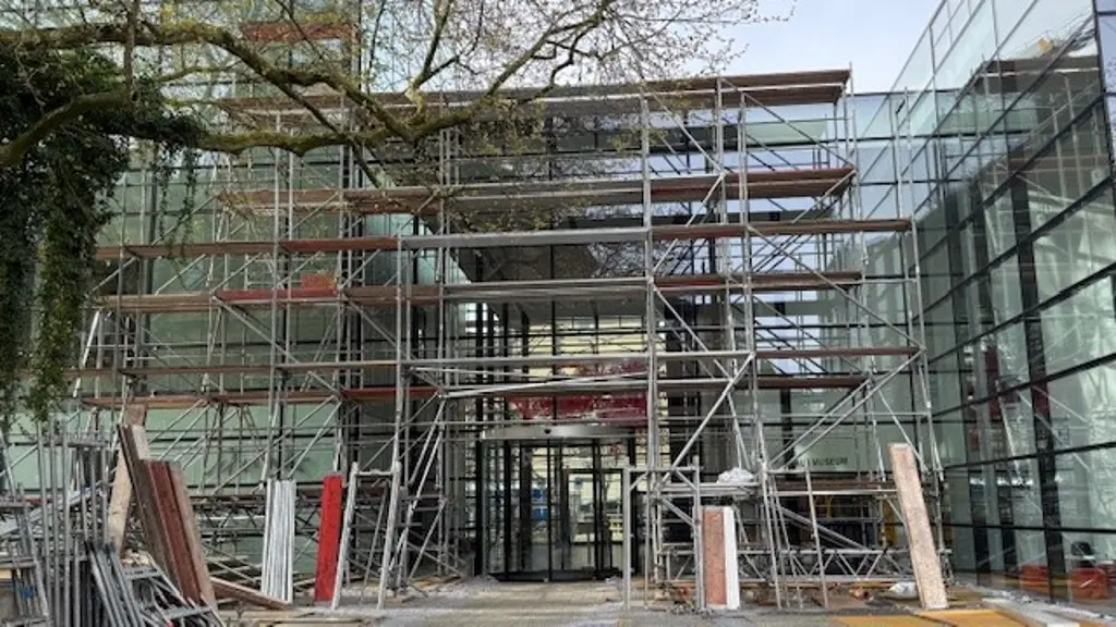 Eine Au&szlig;enaufnahme eines Glasgeb&auml;udes. Im Vorderfrund steht ein Ger&uuml;st.