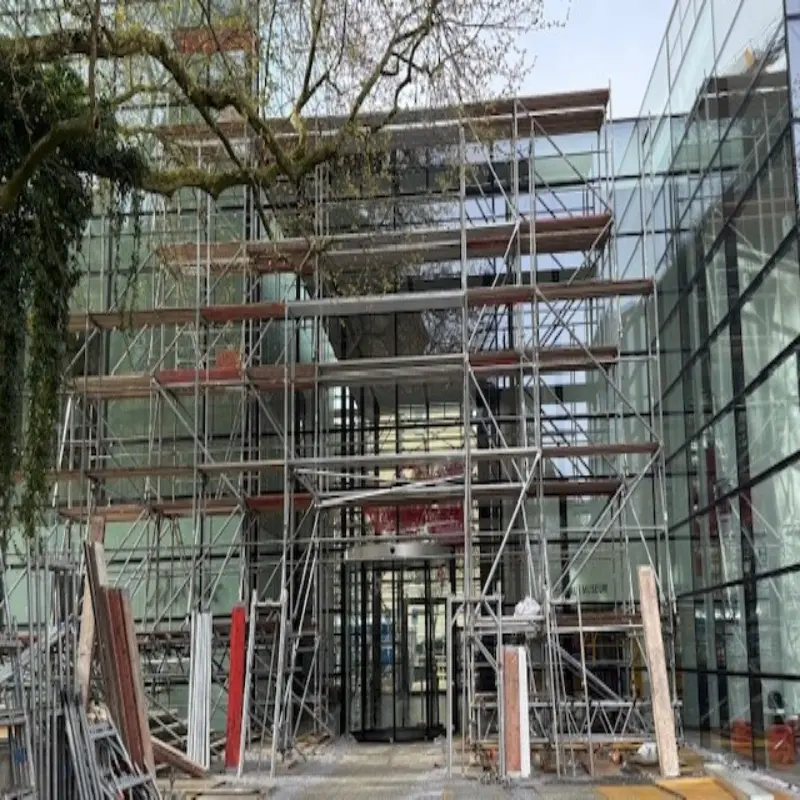 Eine Au&szlig;enaufnahme eines Glasgeb&auml;udes. Im Vorderfrund steht ein Ger&uuml;st.