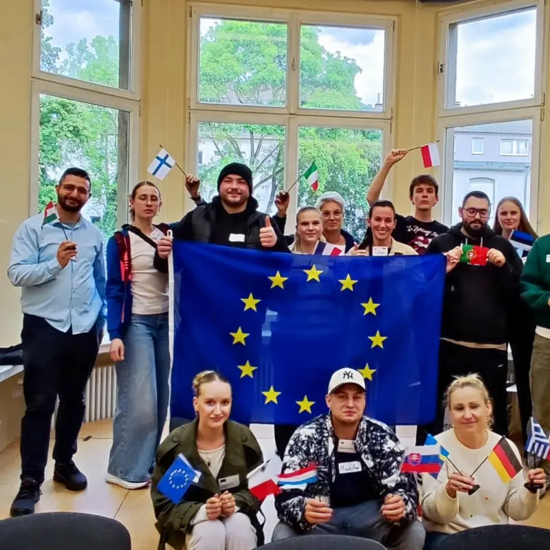 Gruppenfoto: Mehrere Sch&uuml;ler posieren mit einer gro&szlig;en EU-Flagge und vielen kleinen L&auml;nderflaggen.