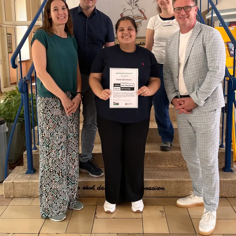 Gruppenfoto: Alexandra L&ouml;pke und Dominik Severing (Lehrkr&auml;fte), Nupelda &Ouml;zmen (Sch&uuml;lervertretung), Marion Rosenberg (KI) und Christian Fischer (Schulleitung) mit der Jubil&auml;umsurkunde.