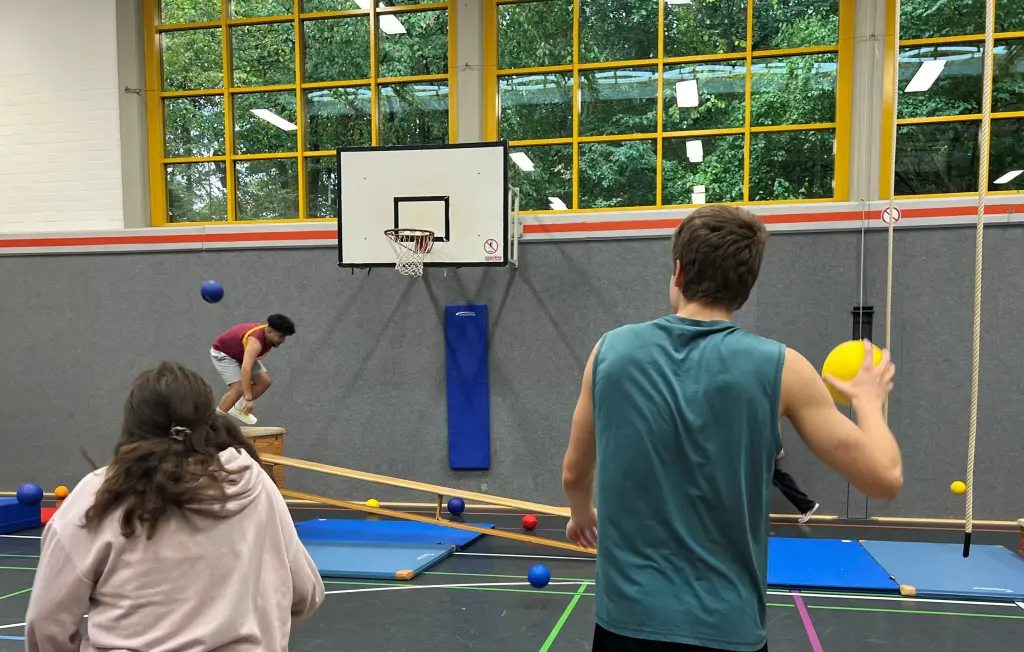 Foto: Ein Schüler wirft einen Ball auf einen anderen Schüler, der den Parcours durchläuft.
