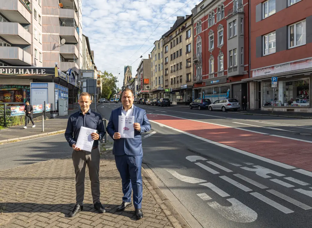 Foto: Patrick Bänsch Dennis Rehbein präsentieren die Kaufverträge auf einer Verkehrsinsel auf der Altenhagener Straße.