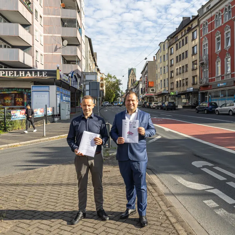 Foto: Patrick Bänsch Dennis Rehbein präsentieren die Kaufverträge auf einer Verkehrsinsel auf der Altenhagener Straße.