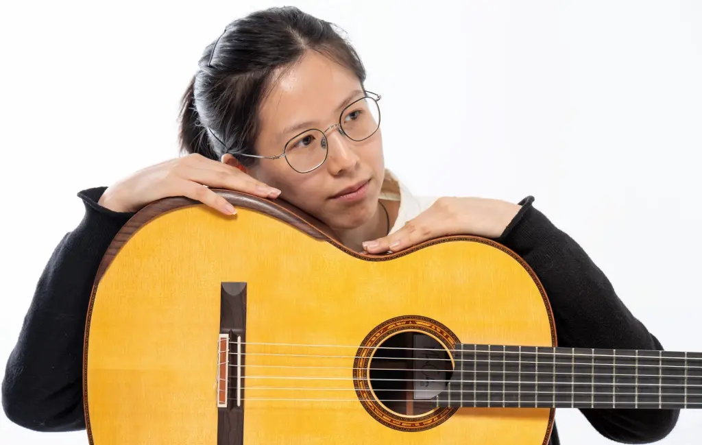Foto: Siqi Chen st&uuml;tzt ihren Kopf auf die Gitarre.
