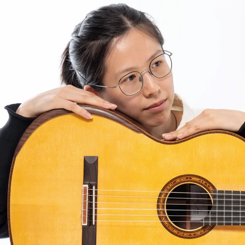 Foto: Siqi Chen st&uuml;tzt ihren Kopf auf die Gitarre.