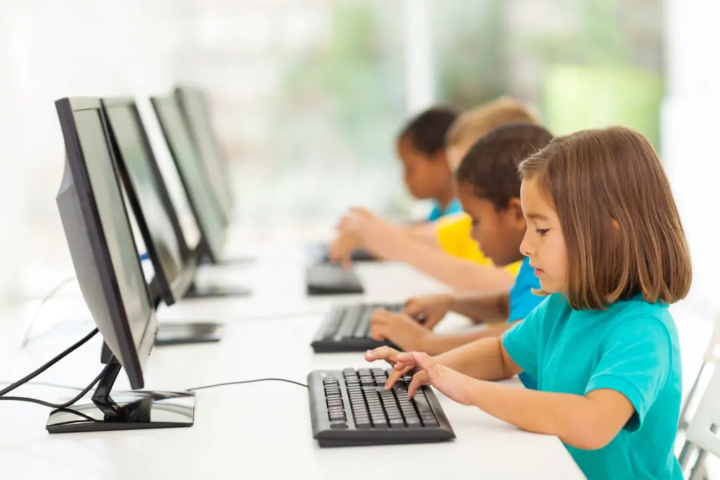 Symbolfoto: Mehrere Kinder sitzen vor Computerbildschirmen.
