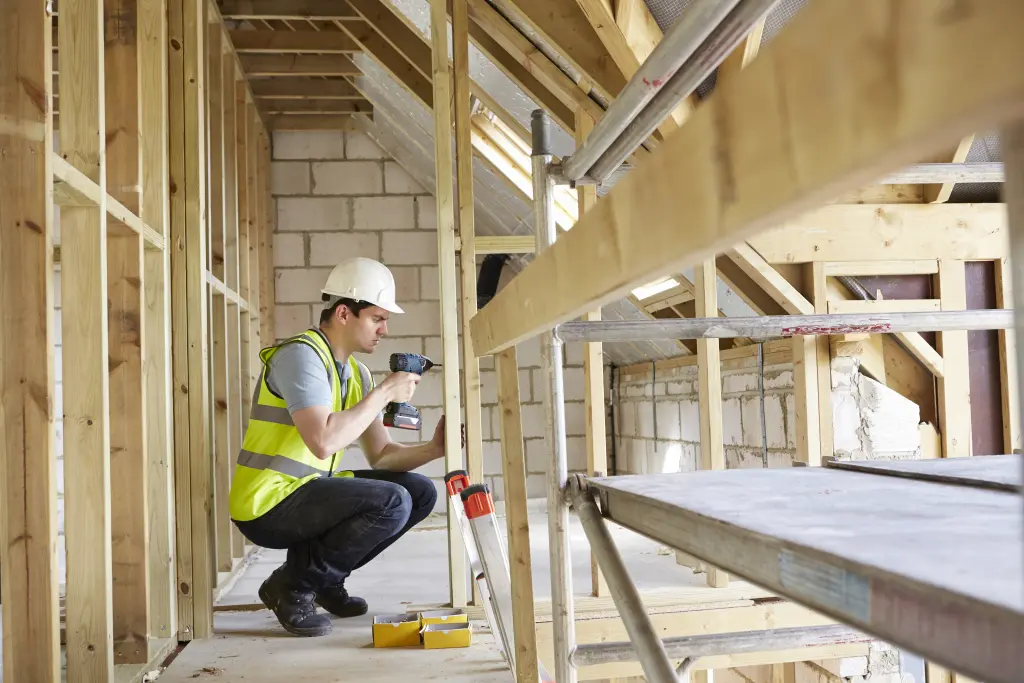 Foto: Ein Mensch auf einer Baustelle mit einer Warnweste und einem Helm.