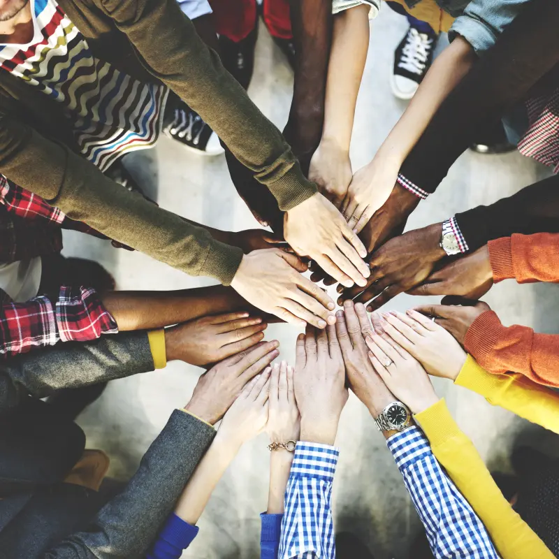 Symbolbild: Viele H&auml;nde mit unterschiedlichen Hautt&ouml;nen ber&uuml;hren sich in der Mitte.