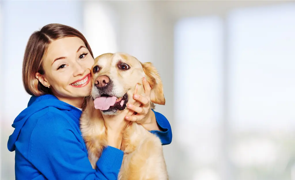 Foto: Eine lächelnde Frau umarmt einen Hund.