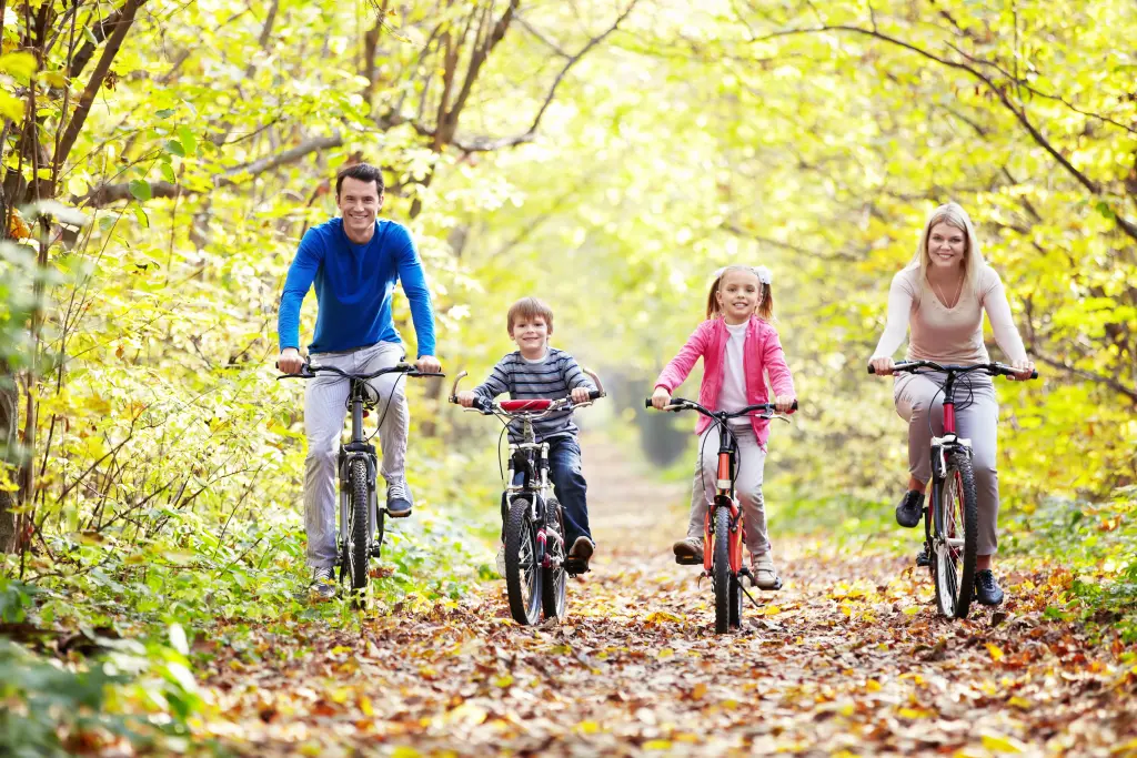 Foto: Eine vierk&ouml;pfige Familie f&auml;hrt im Wald Fahrrad.