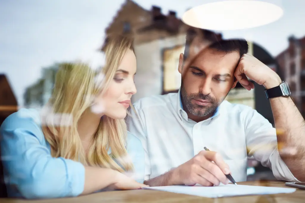 Foto: Ein Mann und eine Frau sitzen an einem Tisch und schauen gemeinsam auf ein beschriebenes Blatt papier.