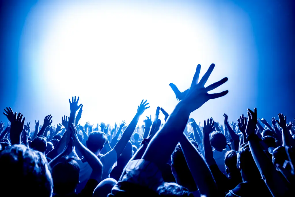Foto: Viele Menschen heben ihre Hände auf einem Konzert oder einer Party.
