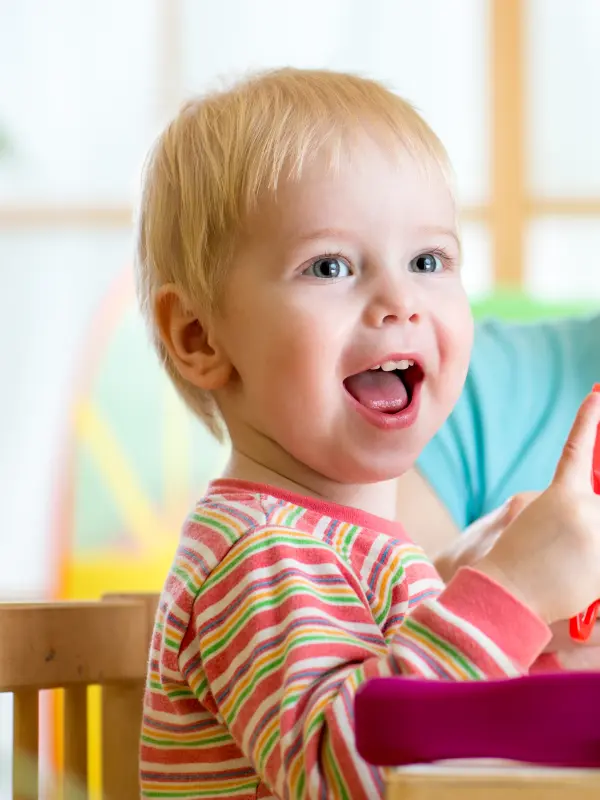 Foto: Zwei spielende Kinder mit einer weiblichen Pflegeperson.
