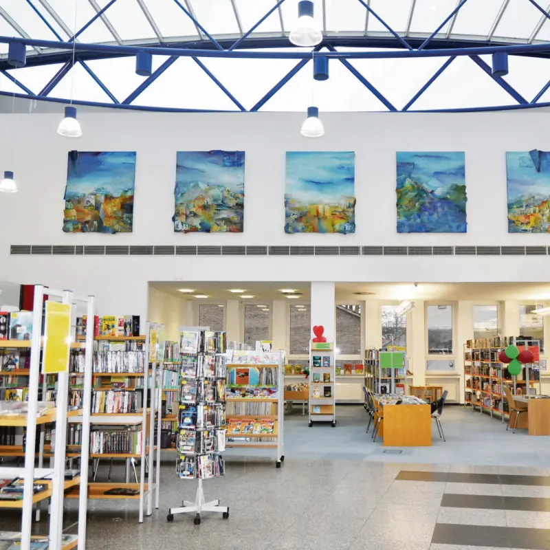 Foto: Hauptraum der Stadtteilbücherei Hohenlimburg mit einer hohen Decke und vielen Bücherregalen.