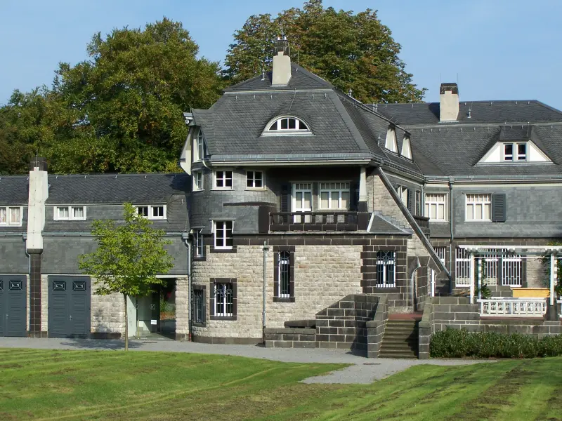 Foto: Der Hohenhof von außen mit grauem Backstein und einer großen Rasenfläche vor dem Gebäude.