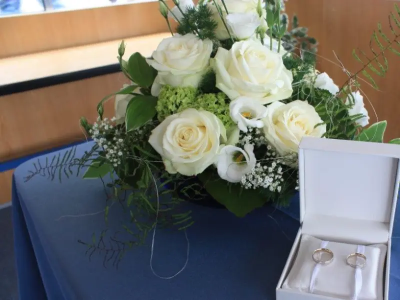 Foto: Eine Schachtel mit Eheringen liegt neben einem Blumenstrauß.