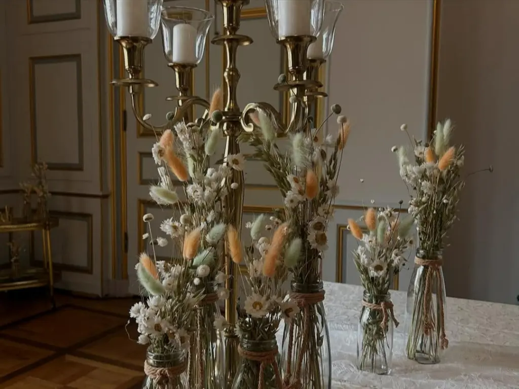 Foto: Mehrere Blumengedecke auf einem langen Tisch mit einer Tischdecke aus Samt.
