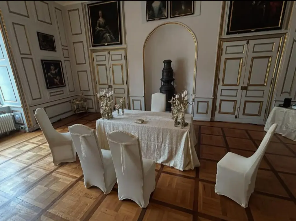 Foto: Ein Tisch mit samtener Tischdecke und Blumengedeck in einem großen Festsaal.