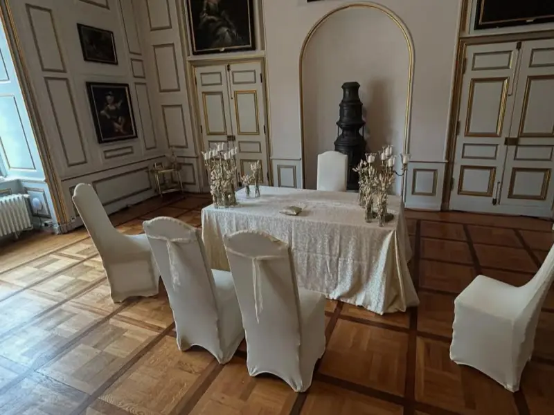 Foto: Ein Tisch mit samtener Tischdecke und Blumengedeck in einem großen Festsaal.