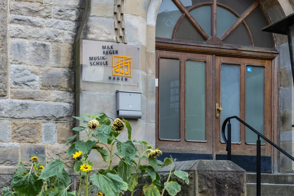Foto: Die Eingangstreppe der Max-Reger-Musikschule mit großen Sonnenblumen daneben.