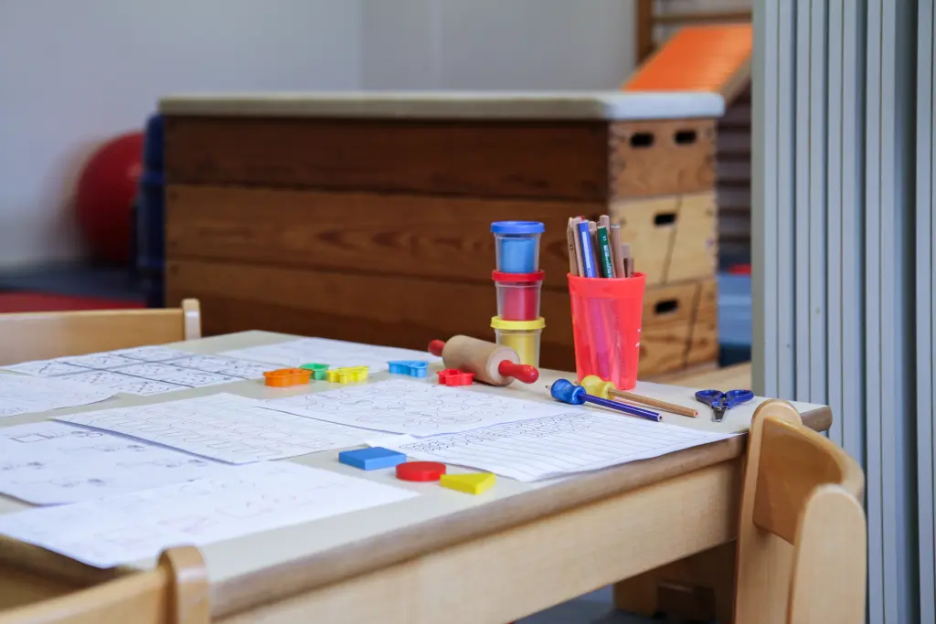 Foto: Ein Kindertisch mit Ausmalbildern und einer Box mit Stiften.