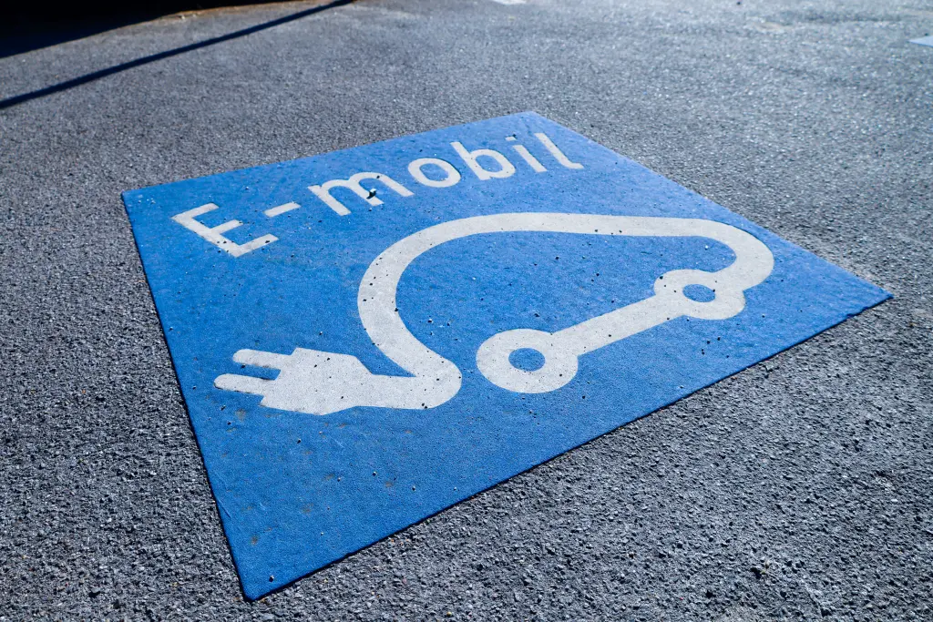 Foto: Ein auf Asphalt gedrucktes Symbol eines E-Autos, das eine Ladesäule anzeigt.