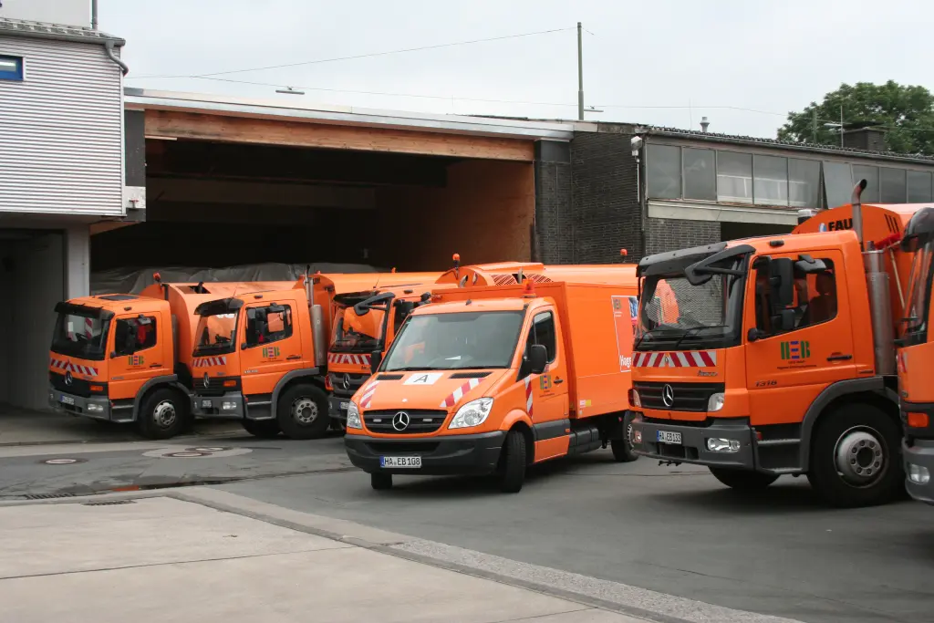 Foto: Vor einer Garage stehen mehrere große Müllentsorgungsfahrzeuge.