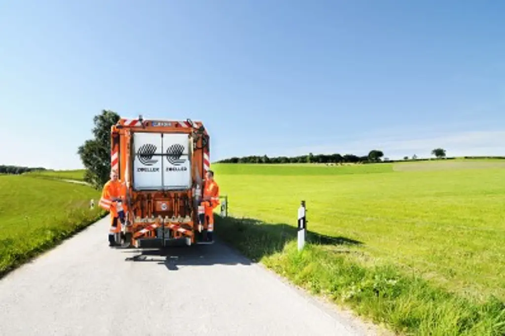 Ein Müllwagen der Firma HEB fährt über einen Feldweg.