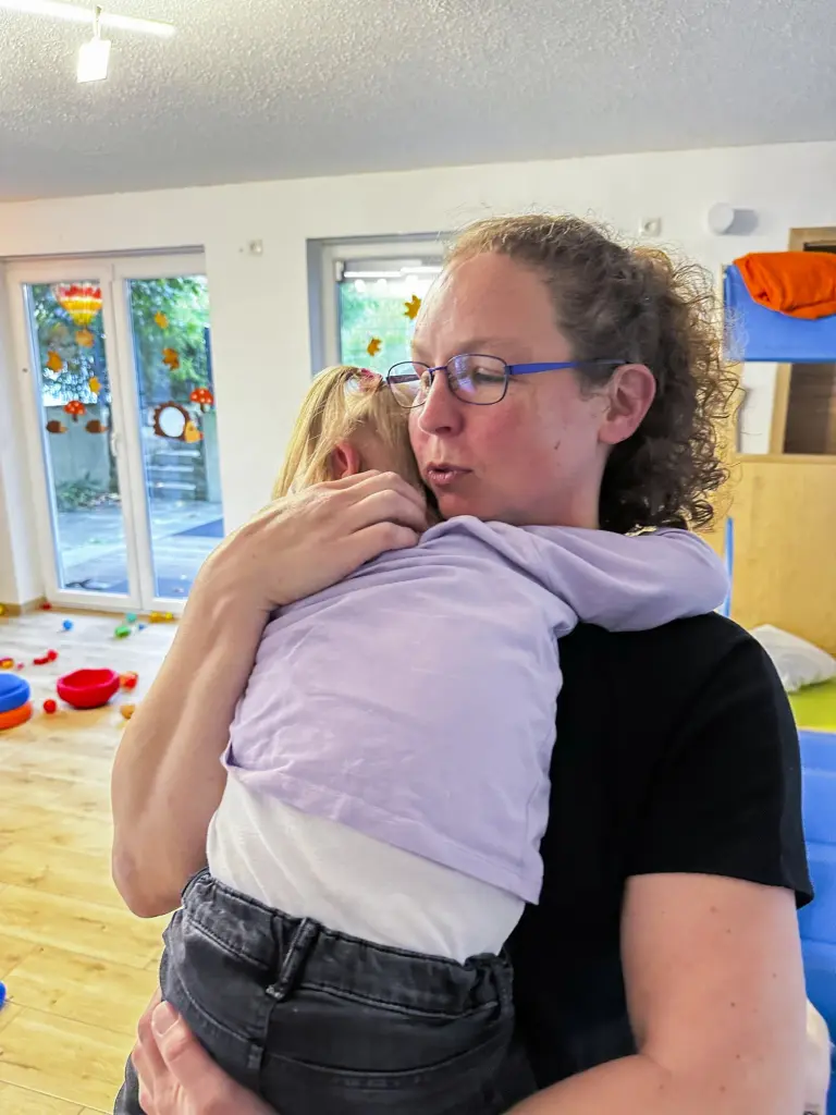 Foto: Ein Kind auf dem Arm einer Tagespflegekraft.