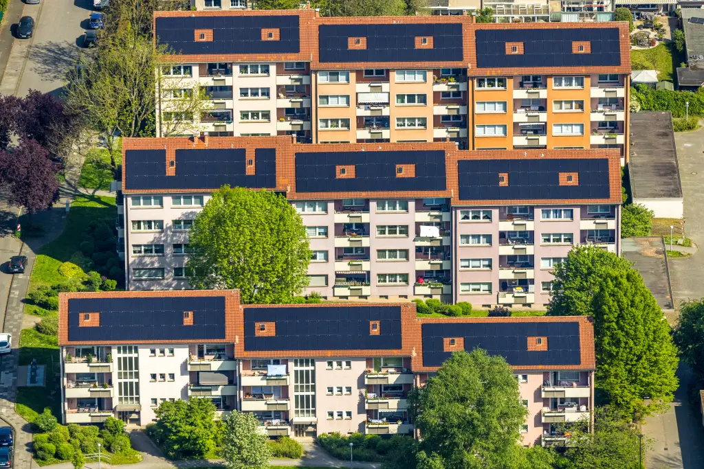 Foto: Mehrere Wohnblöcke mit Solaranlägen auf den Dächern aus der Luft.
